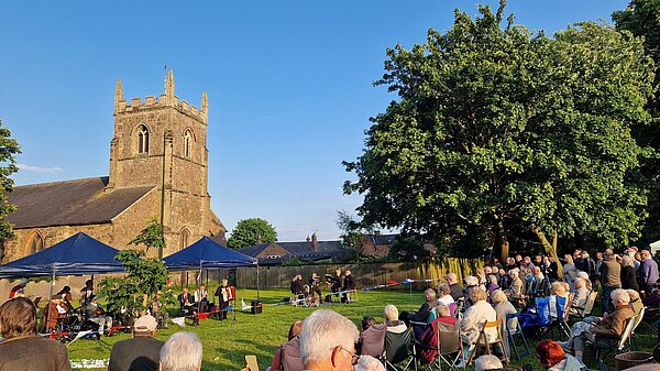 Church in Countesthorpe with blue sky trees and people 